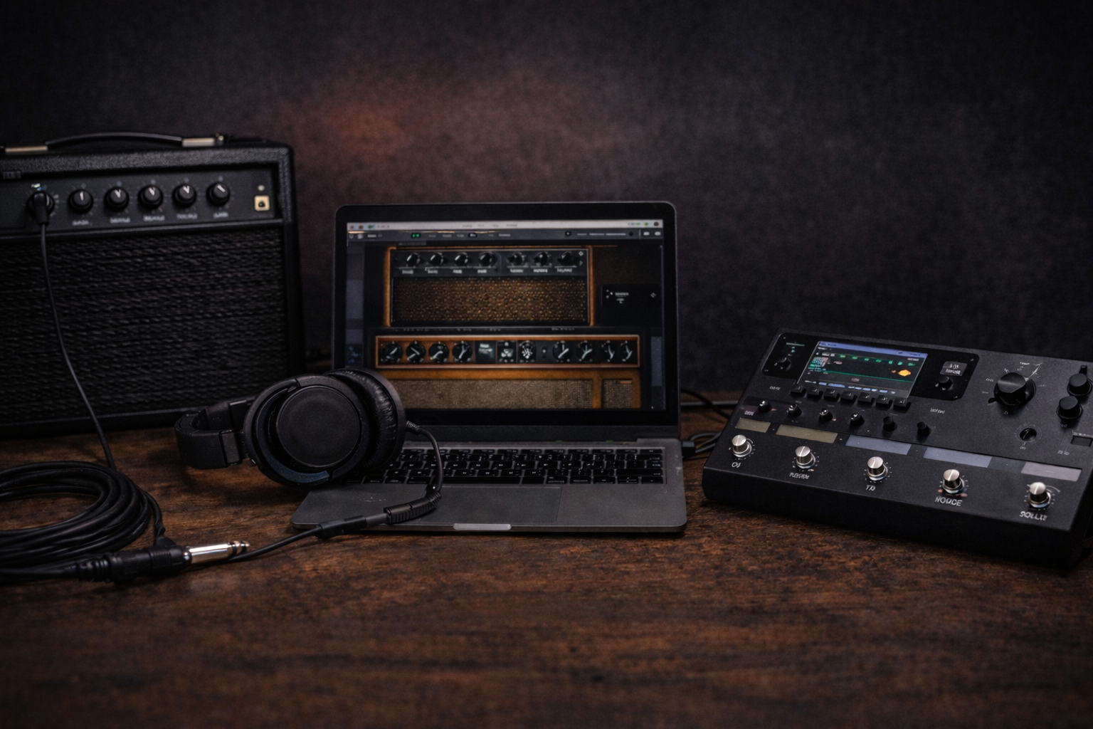 Home guitar rig with a compact practice amp, a laptop running amp sim software, and a multi-FX floor unit on a dark wooden desk