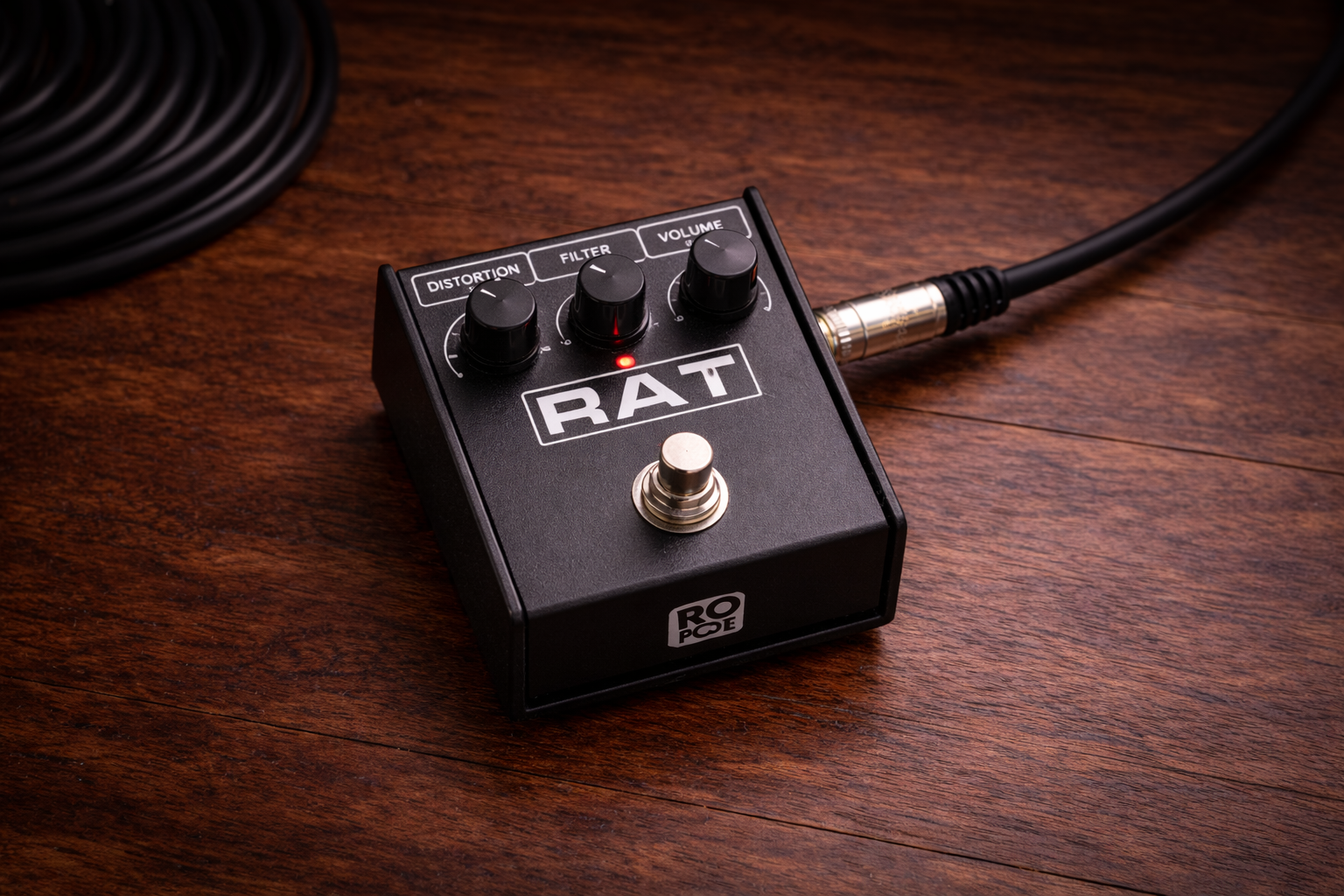 pro co rat distortion pedal: slightly wider close-up of a Pro Co RAT pedal on a wooden desk
